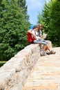 Couple of backpackers sitting on bridge and reading map Royalty Free Stock Photo