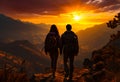 Couple of backpackers standing on the high rock. Travelers looking at beautiful mountains at sunset Royalty Free Stock Photo