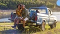 Couple With Backpacks In Pick Up Truck On Road Trip By Lake Drinking Beer Royalty Free Stock Photo