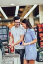 Couple with bank card buying food at grocery store or supermarket self-checkout Royalty Free Stock Photo