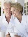 Couple In Bathrobes With Cups On Verandah Royalty Free Stock Photo