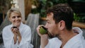 Couple in bathrobes drinking green tea, enjoying romantic wellness weekend in spa. Concept of Valentine's Day.