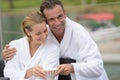 Couple in bathrobes sharing drink outdoors Royalty Free Stock Photo