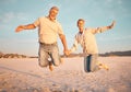 Couple, beach and active seniors hold hands while jumping in sand, happy and excited at sunset. Love, family and freedom Royalty Free Stock Photo