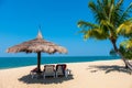 Couple beach chairs and coconut palm tree on tropical beach with sea and blue sky background. Royalty Free Stock Photo