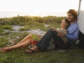 Couple On Beach Leaning On Campervan