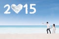 Couple on beach pointing at number 2015 Royalty Free Stock Photo