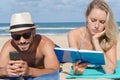 Couple on beach reading book