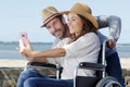 couple by beach in wheelchair taking selfie Royalty Free Stock Photo