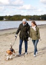 Couple with beagle dog walking along autumn beach Royalty Free Stock Photo