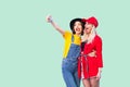 Couple of beautiful stilysh hipster best friends in fashionable clothes hugging with love, posing for camera and making selfie or Royalty Free Stock Photo