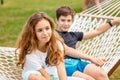 Couple of beautiful teens, first love. Girl and guy are sitting next to each other in the park