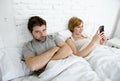 couple in bed husband frustrated upset unsatisfied while wife using mobile phone Royalty Free Stock Photo