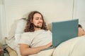 Couple in bed. The man entertaining with the laptop while the woman sleeps Royalty Free Stock Photo