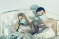 Couple in bed on self-quarantine with masks suffering from flu or virus Royalty Free Stock Photo