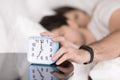 Couple being woken by alarm, man turning off ringing clock Royalty Free Stock Photo
