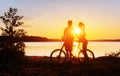 Couple on a bicycle at sunset by the lake