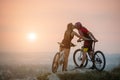 Couple bicyclist with mountain bikes on the hill at sunset Royalty Free Stock Photo