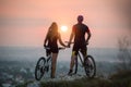 Couple bicyclist with mountain bikes on the hill at sunset Royalty Free Stock Photo