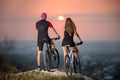 Couple bicyclist with mountain bikes on the hill at sunset Royalty Free Stock Photo