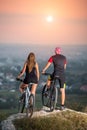 Couple bicyclist with mountain bikes on the hill at sunset Royalty Free Stock Photo