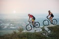 Couple bicyclist with mountain bikes on the hill at sunset Royalty Free Stock Photo