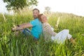 Couple in big green grass back to back. Man and woman sitting in the field in summer day. Royalty Free Stock Photo