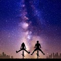 Couple on bikes at night. Cyclist with legs apart. Stars and Milky Way