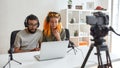 Couple of bloggers, young man and woman in headphones watching something on laptop, making faces while recording Royalty Free Stock Photo