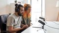 Couple of bloggers, young man and woman in headphones watching something on laptop while recording reaction video blog Royalty Free Stock Photo