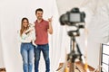Couple of boyfriend and girlfriend with dog posing as model at photography studio smiling happy pointing with hand and finger to Royalty Free Stock Photo