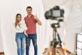 Couple of boyfriend and girlfriend with dog posing as model at photography studio smiling happy and positive, thumb up doing Royalty Free Stock Photo