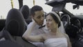 Couple of bride and groom in convertible. Action. Beautiful couple of newlyweds in car in summer. Couple plays newlyweds Royalty Free Stock Photo