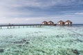 Couple on bridge to Water villas on crystal clear water at tropical island