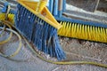 A couple of brooms and a dirty floor of a workshop.