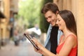 Couple browsing a tablet in the street