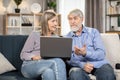 Couple browsing webstore via laptops while sitting on couch Royalty Free Stock Photo