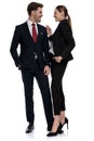 Couple in business suits standing together with hands in pockets