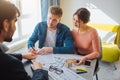 Couple buy or rent apartment together. Business deal. Young man put signature on documents and look at realtor. He point Royalty Free Stock Photo