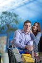 A couple of buyers with a shopping cart with purchases focus on Royalty Free Stock Photo