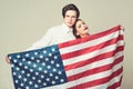 Couple on calm faces holds flag of USA. Guy and girl proud to be americans, grey background. Language school concept