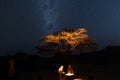 Couple at campfire, camping under starry sky and Milky Way arch. Adventure into the wild, Namibia road trip, vacation in Africa. Royalty Free Stock Photo