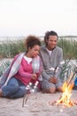 Couple Camping On Beach And Toasting Marshmallows