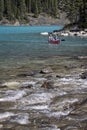 Couple canoeing in front of turbulent river entering glacial lake Moraine in Banff National Park, Alberta, Canada Royalty Free Stock Photo