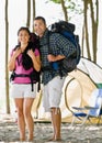 Couple carrying backpacks at campsite