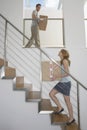 Couple Carrying Boxes Upstairs In New Home