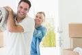 Couple carrying rolled rug after moving in a house