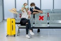 Couple Caucasian lovers man and woman with mask sit on chair with social distance and selfie together in airport during flight for Royalty Free Stock Photo