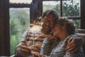 Couple celebrate alone at home with smile and fire sparkler sitting on the couch qieh outdoor nature view. Happy caucasian people Royalty Free Stock Photo