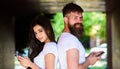 Couple chatting smartphones. Girl and bearded man stand back to back porch or underground. Couple ignore real Royalty Free Stock Photo